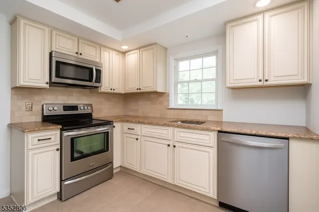 a kitchen with white cabinets and stainless steel appliances