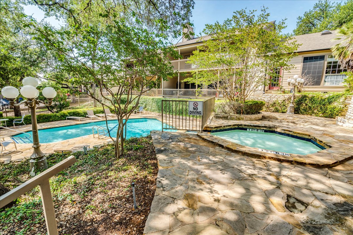 3809 Spicewood Springs Road, Unit 127 Austin, TX 78759 - Photo 28 of 29 An inviting stone patio surrounds a sparkling pool and a cozy spa, perfect for relaxation.