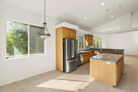 a kitchen with stainless steel appliances granite countertop a refrigerator a sink a stove and a refrigerator