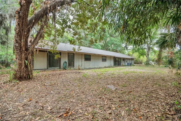 a view of a house with a yard and large tree
