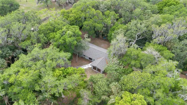 an aerial view of residential house with outdoor space and trees all around