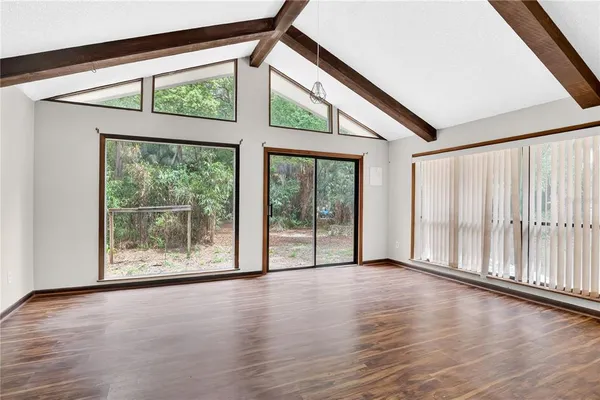 a view of an empty room with wooden floor and a window