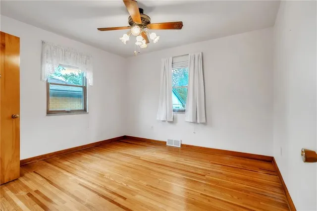 a view of empty room with window and wooden floor