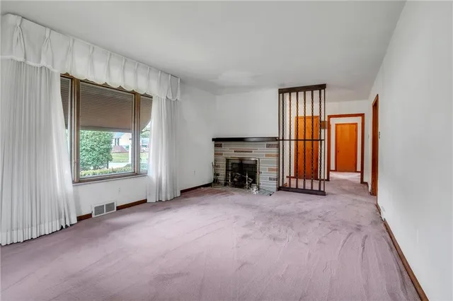 an empty room with windows and fireplace