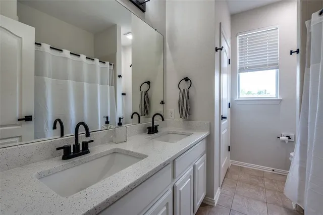 a bathroom with double vanity sink a mirror and a shower