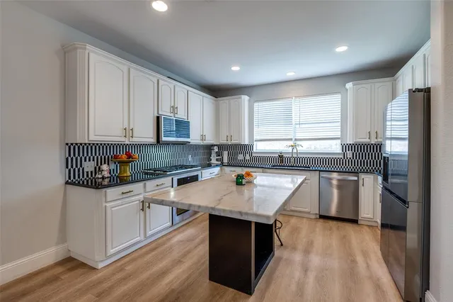 a kitchen with a sink a counter top space cabinets and stainless steel appliances
