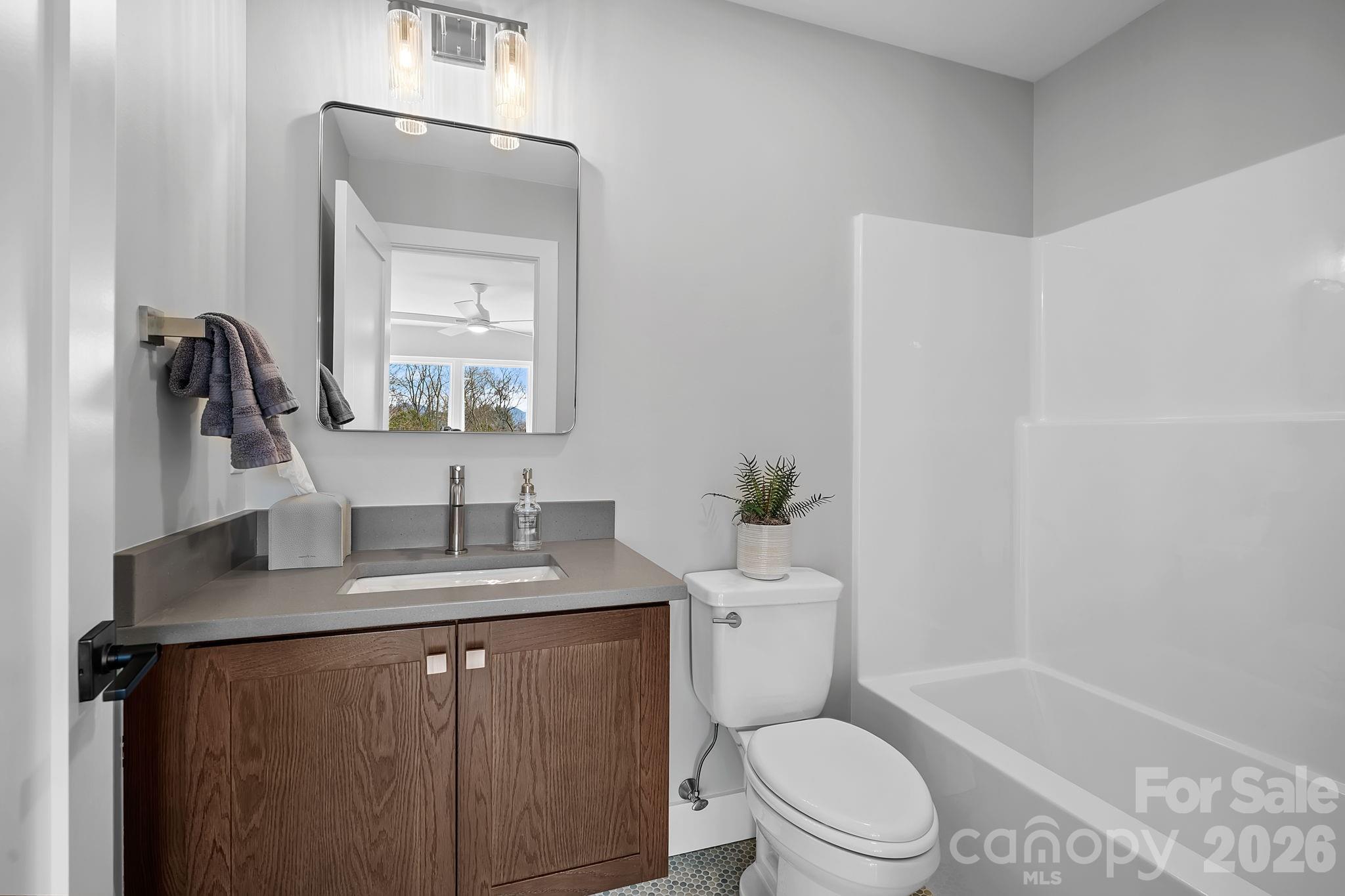 5 Gudger Road Asheville, NC 28715 - Photo 38 of 47 a bathroom with a granite countertop sink a toilet a mirror and shower