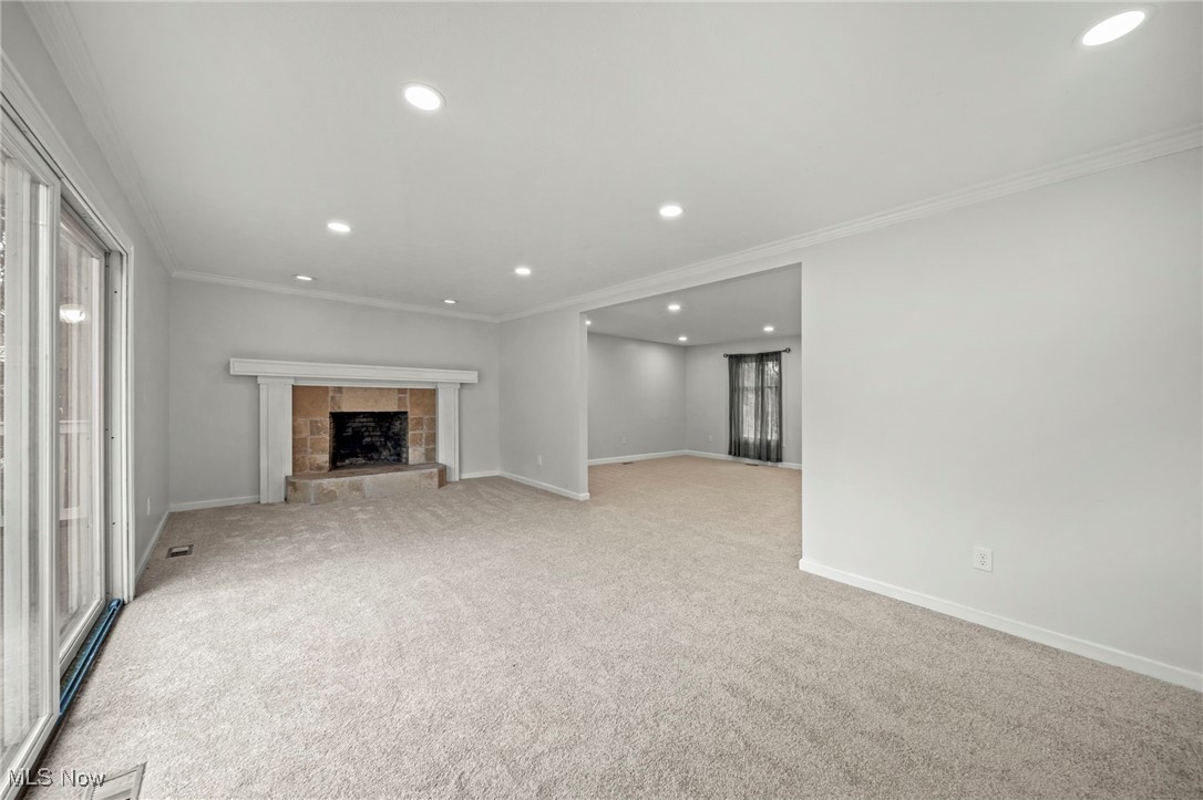 91 Paradise Road Painesville, OH 44077 - Photo 8 of 39 Unfurnished living room featuring ornamental molding, recessed lighting, carpet, a fireplace with raised hearth, and plenty of natural light
