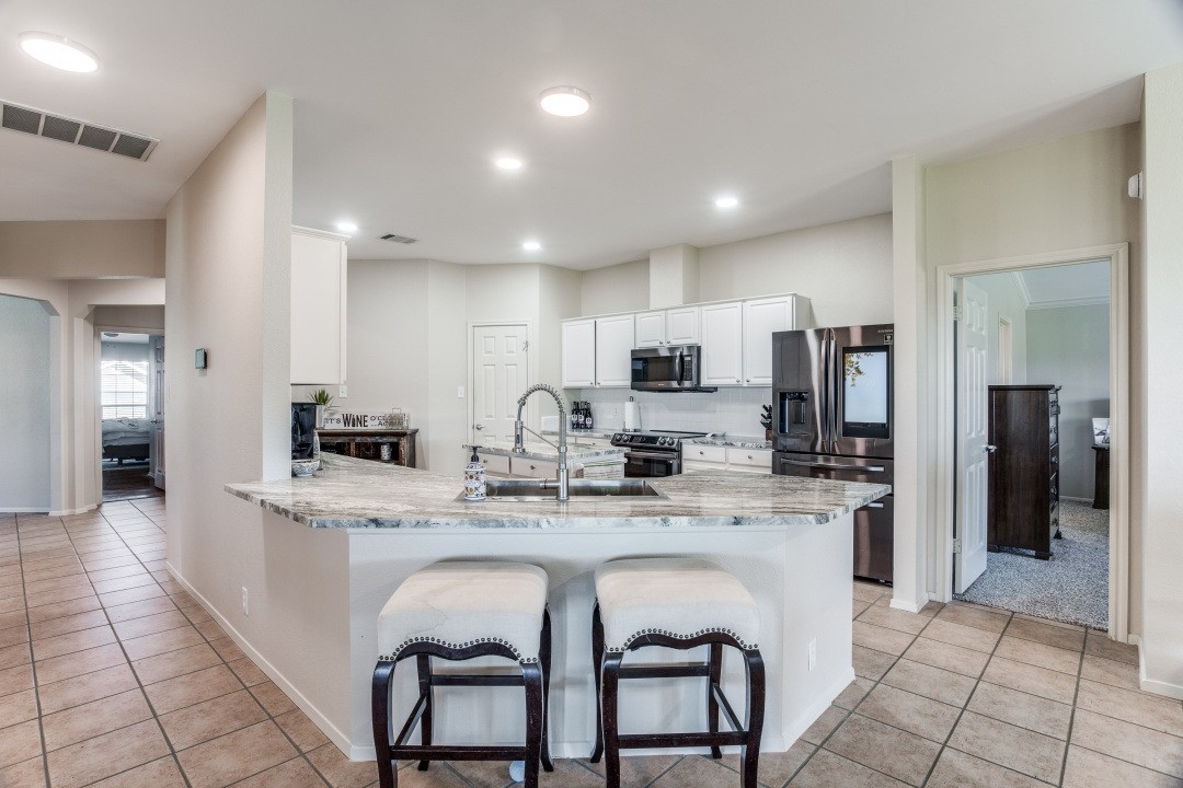 a large kitchen with stainless steel appliances kitchen island granite countertop a table chairs sink and cabinets