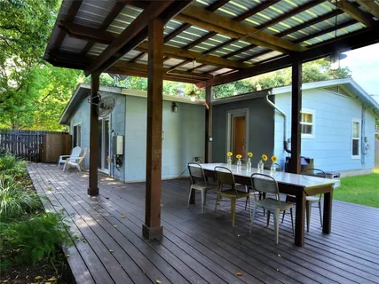 a view of a patio with table and chairs with wooden floor and roof with a barbeque grill