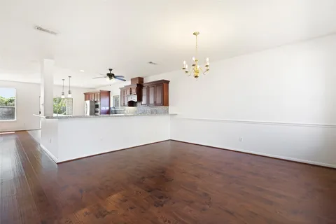 an empty room with kitchen view and wooden floor