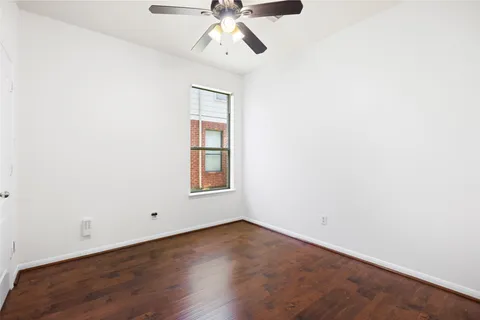 an empty room with wooden floor ceiling fan and windows