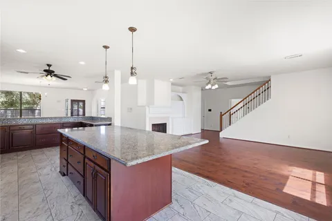 a kitchen with stainless steel appliances granite countertop a kitchen island a stove a sink and a wooden floors
