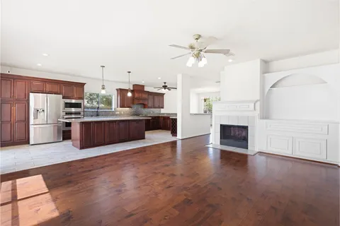 a view of kitchen with kitchen island wooden floor and stainless steel appliances