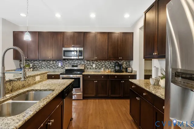 a kitchen with stainless steel appliances granite countertop wooden cabinets a sink dishwasher a stove and a refrigerator