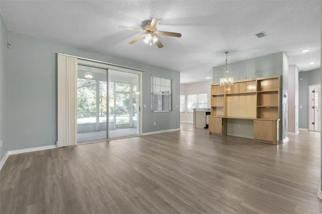 an empty room with wooden floor and kitchen view