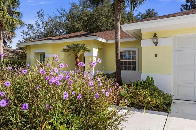 a front view of yellow house with flowers