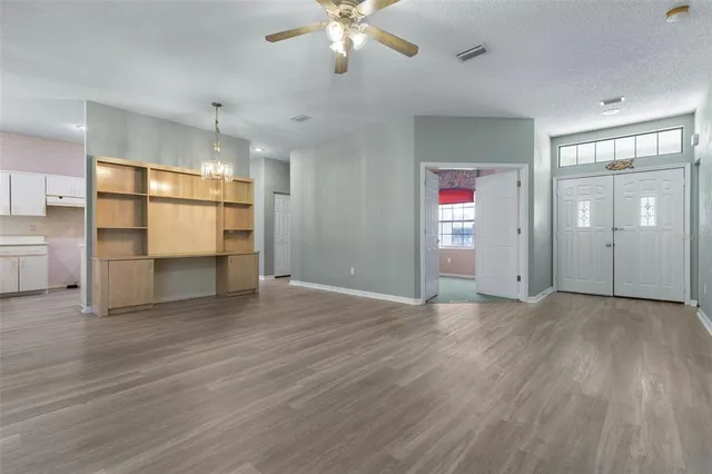 a view of an empty room with wooden floor and chandelier