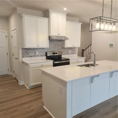 a large kitchen with stainless steel appliances a large counter top a stove a refrigerator and a cabinets