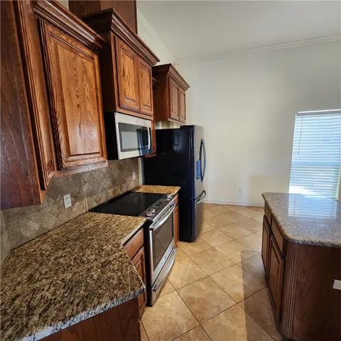 a kitchen with granite countertop a refrigerator and a stove top oven