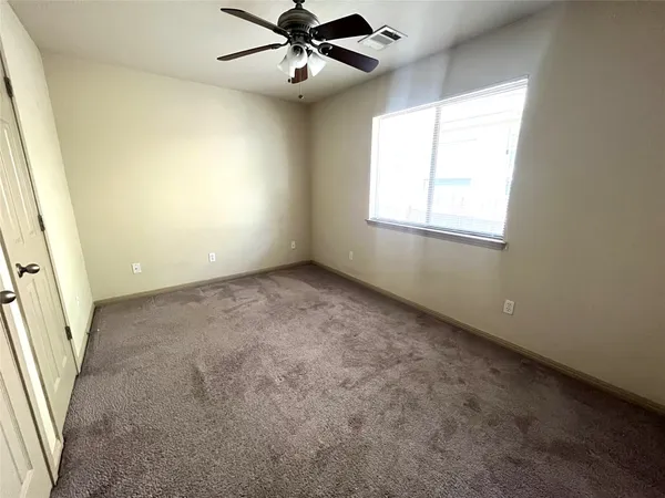 an empty room with windows and ceiling fan