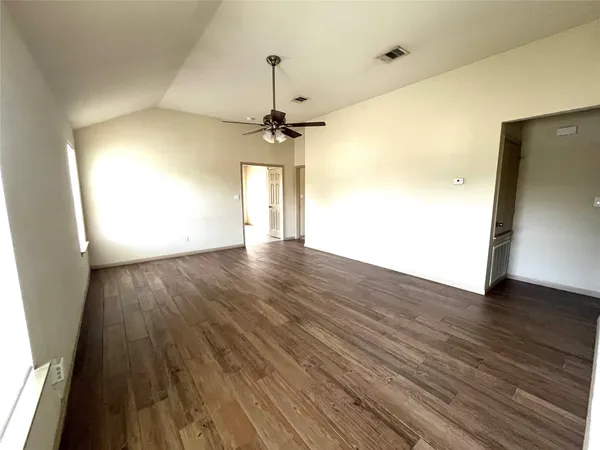 a view of a room with wooden floor a ceiling fan and window