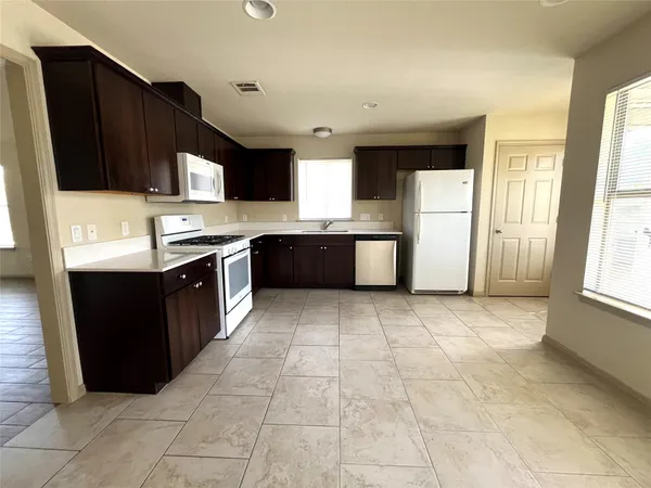 a large kitchen with stainless steel appliances granite countertop a stove a sink dishwasher and a refrigerator
