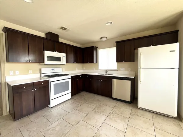 a kitchen with a refrigerator a microwave a sink and cabinets
