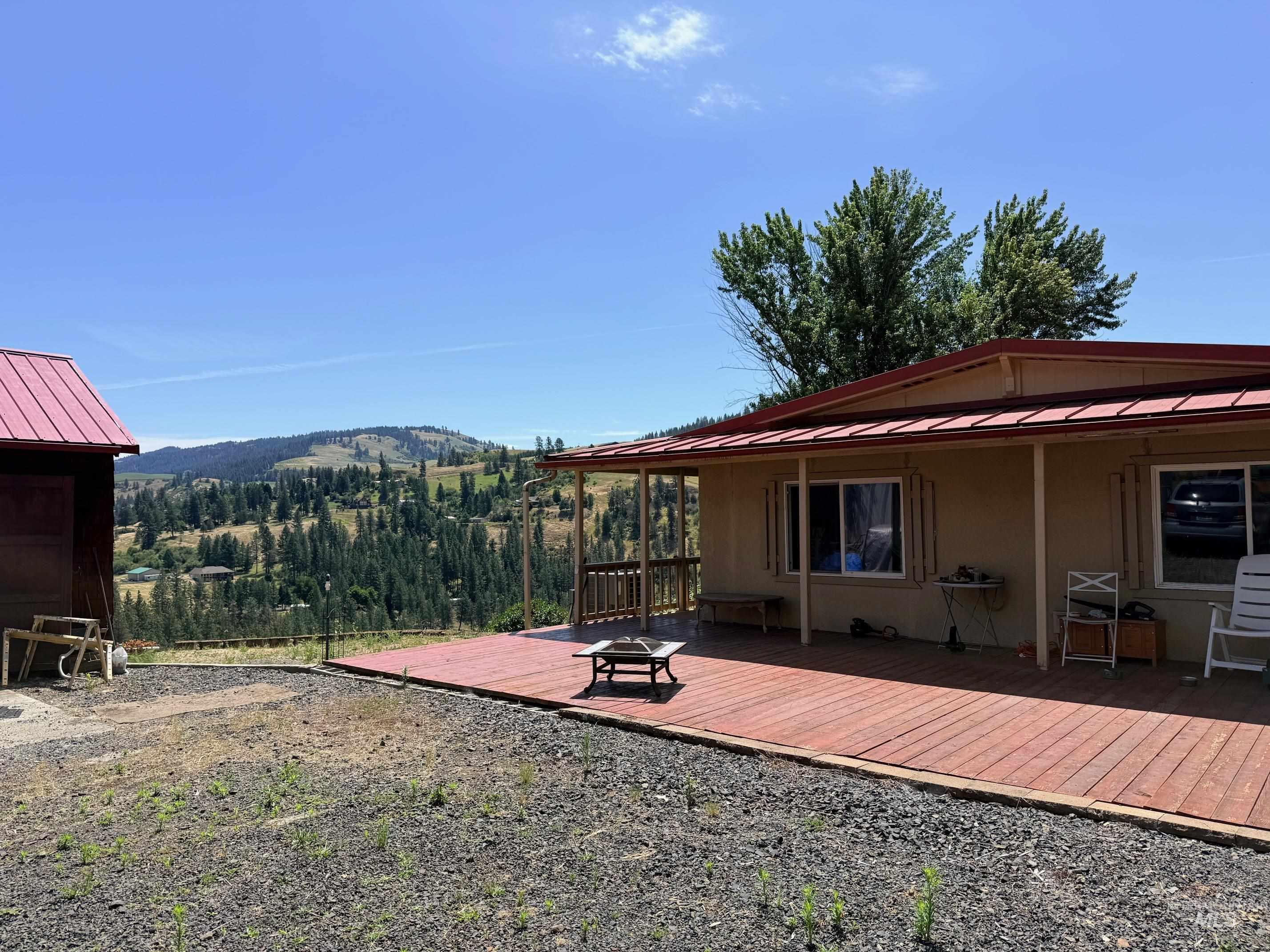 35322 River Road Lenore, ID 83541 - Photo 32 of 42 Expansive outdoor wood deck with a covered patio area, tan exterior siding, and a red metal roof
