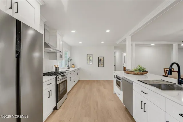 a large kitchen with stainless steel appliances a sink a stove and a refrigerator