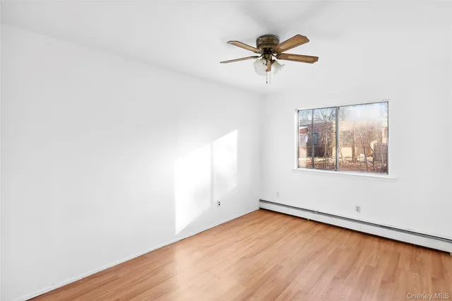 an empty room with wooden floor fan and windows