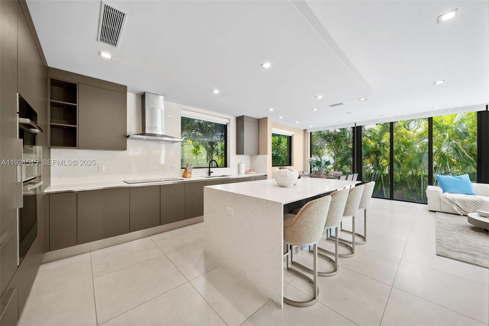 4740 Alton Road Miami Beach, FL 33140 - Photo 7 of 34 a kitchen with stainless steel appliances kitchen island granite countertop a sink and cabinets