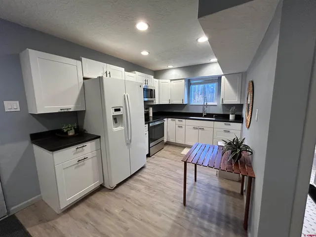 a kitchen with granite countertop a refrigerator stove a sink and dishwasher with wooden floor