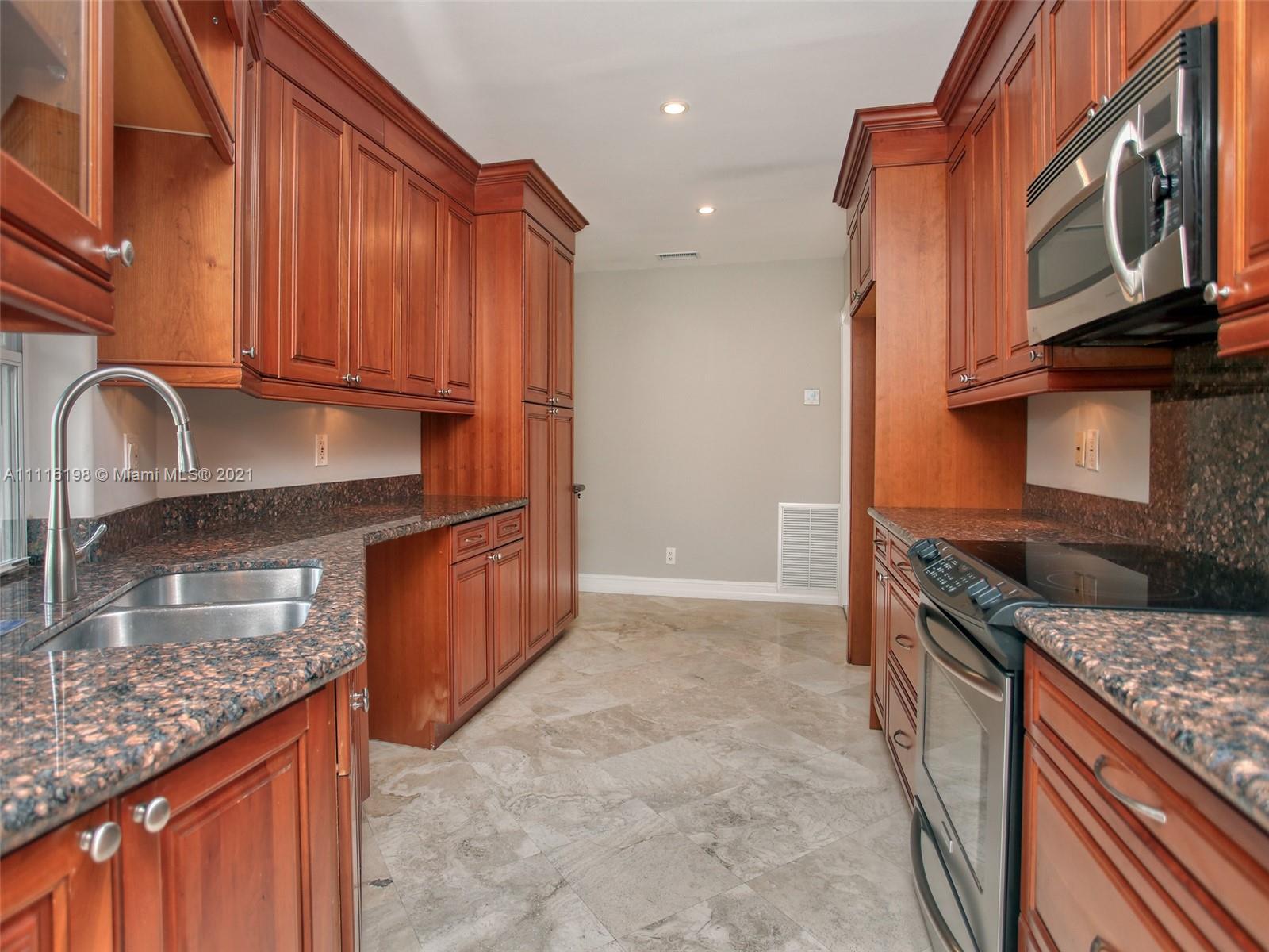 49 Southwest 12th Avenue Boca Raton, FL 33486 - Photo 10 of 30 a kitchen with granite countertop a stove top oven microwave and cabinets