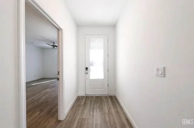 an empty room with wooden floor and a ceiling fan