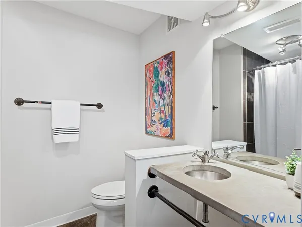 a bathroom with a granite countertop sink a toilet and a mirror