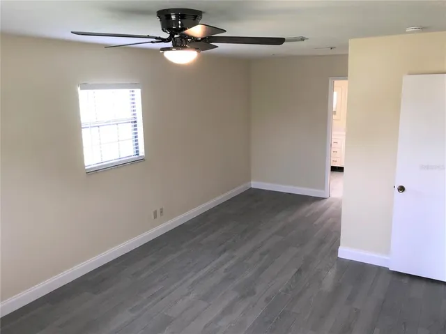 an empty room with wooden floor cabinet and windows