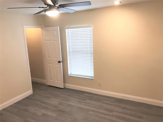 an empty room with a ceiling fan and wooden floor