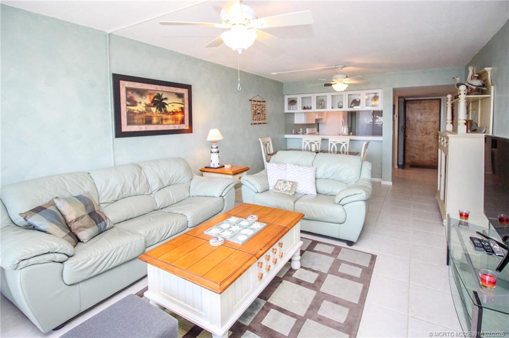 4490 Northeast Sandpebble Trace, Unit 105 Stuart, FL 34996 - Photo 10 of 38 a living room with furniture a flat screen tv and a table