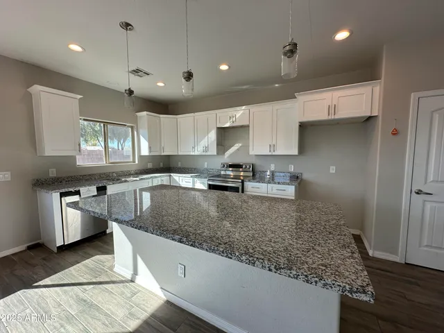 a large kitchen with stainless steel appliances granite countertop a sink refrigerator and cabinets
