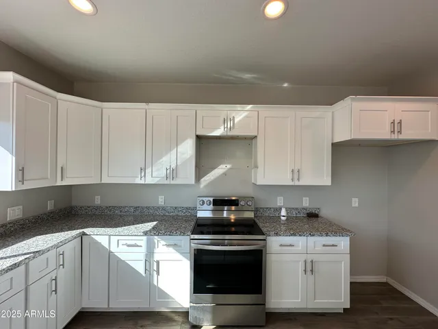 a kitchen with stainless steel appliances granite countertop a stove a sink and white cabinets