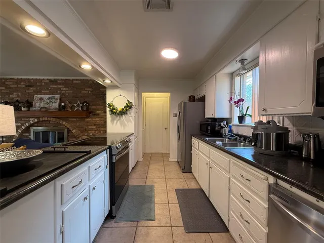 a large kitchen with stainless steel appliances granite countertop a sink and cabinets