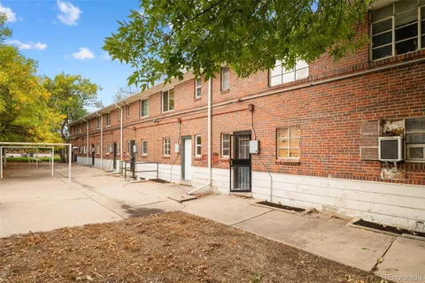 a backyard of a house with large trees and outdoor seating