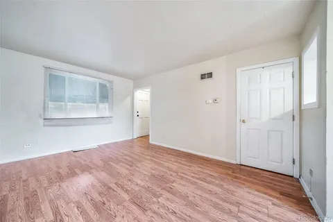 a view of an empty room with wooden floor and a window