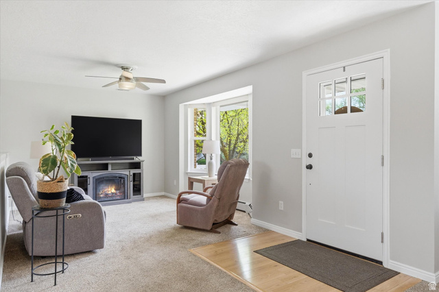 45 West 100 South Mendon, UT 84325 - Photo 5 of 64 Living area featuring plenty of natural light, a lit fireplace, a ceiling fan, and light colored carpet