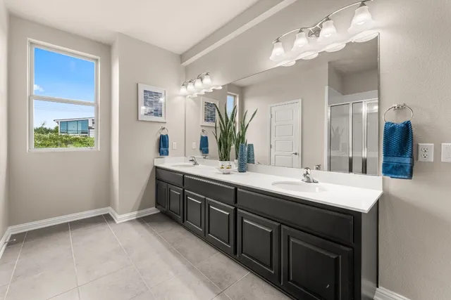 a spacious bathroom with a double vanity sink a mirror and a shower