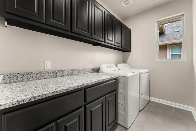 a utility room with granite countertop cabinets washer and dryer
