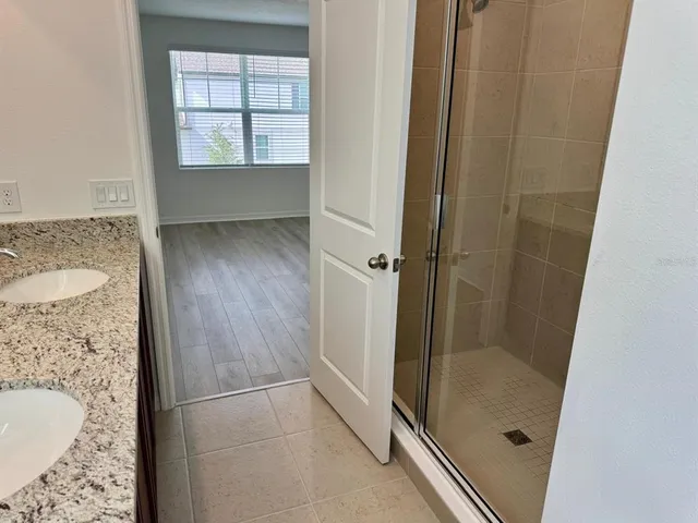 a bathroom with a granite countertop sink a mirror and shower