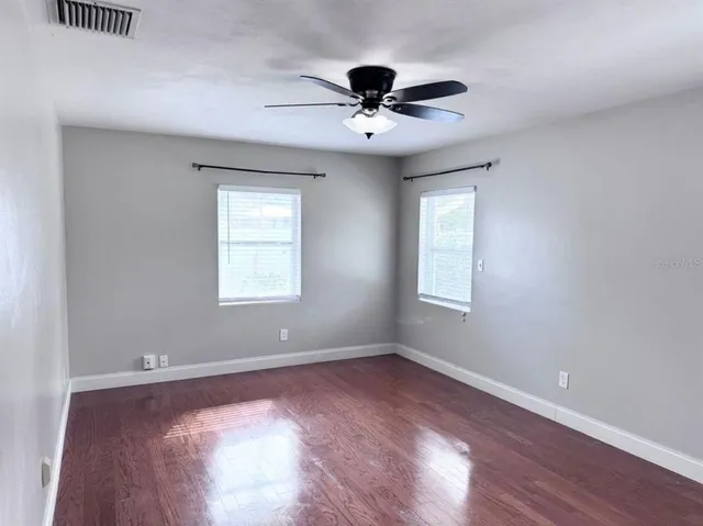 a view of an empty room with wooden floor and a window