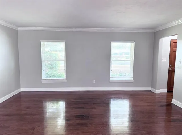 a view of an empty room with wooden floor and a window